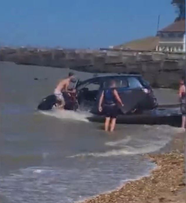 bystanders help man to save his car that got swept off into the sea