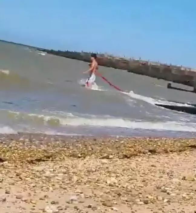 bystanders help man to save his car that got swept off into the sea